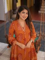 Close-up of a smiling model showcasing the elegant V-neckline with intricate embroidery on a rust orange printed cotton kurta.